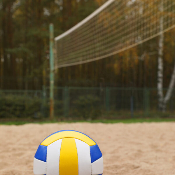 Colorful volleyball ball on sand court, space for text